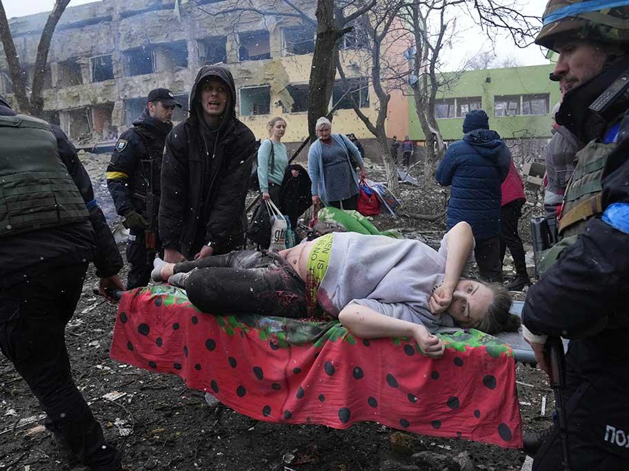 Ukrainian emergency employees and volunteers carry an injured pregnant woman from the shell damaged maternity hospital in Mariupol, Ukraine