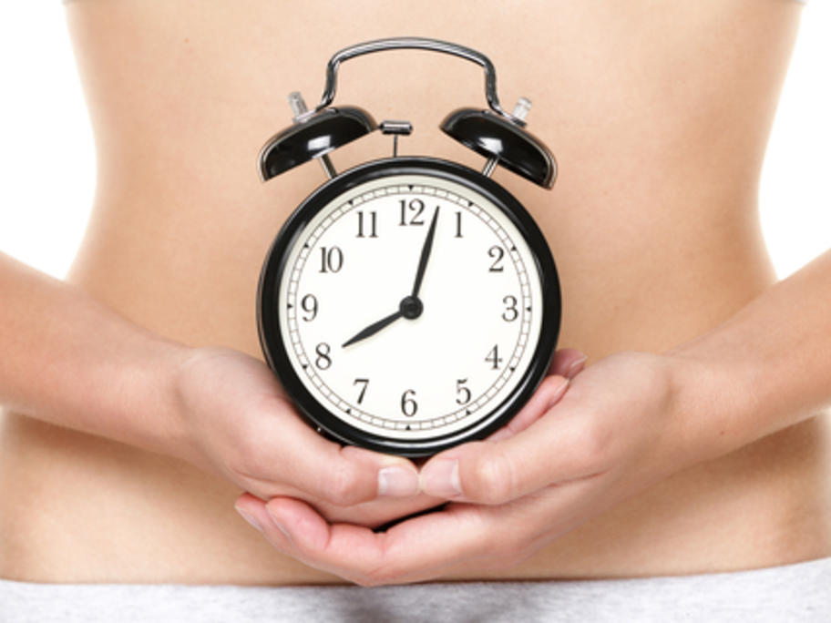 woman holding a clock in front of her navel