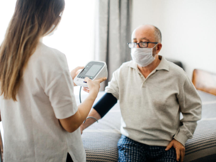senior man in mask having his BP taken by a nurse
