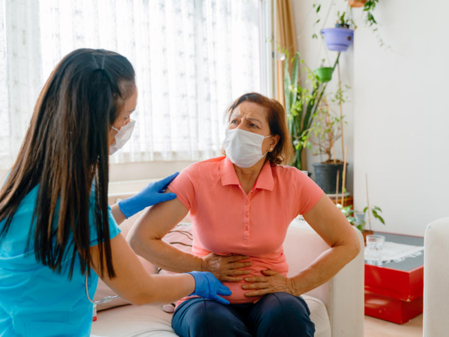 coronavirus patient wearing mask and clutching abdomen
