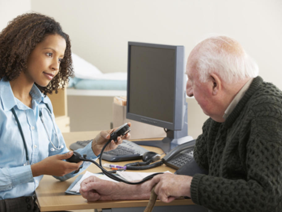 young female doctor taking elderly man's BP
