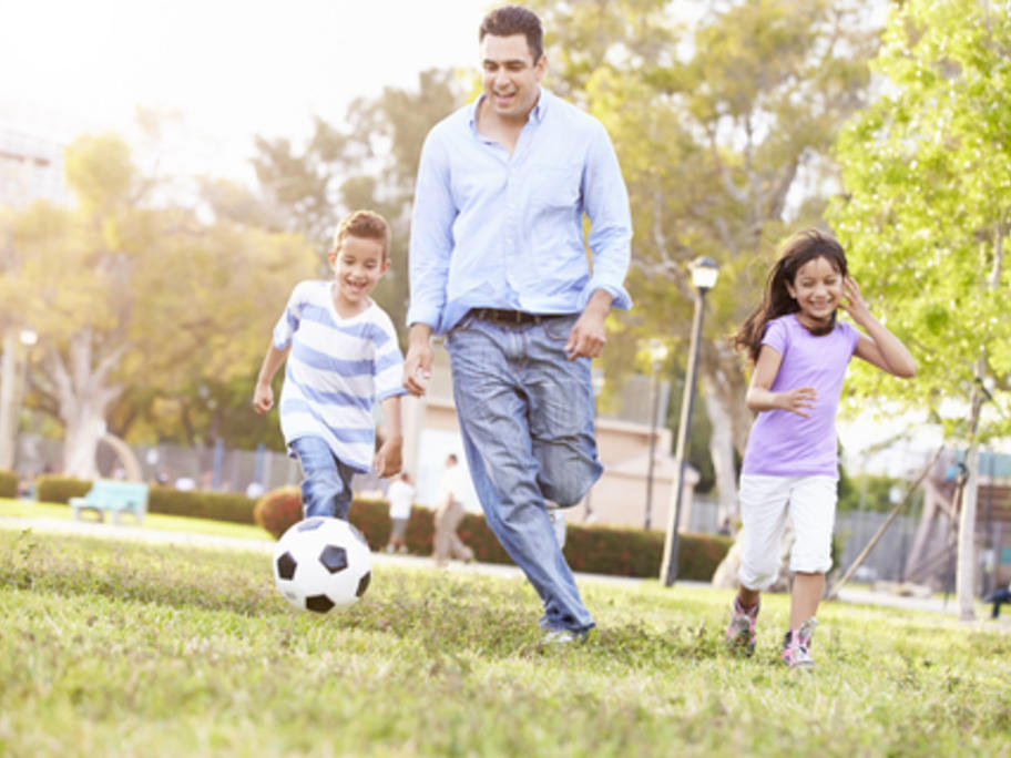 father palying soccer with his son and daughter