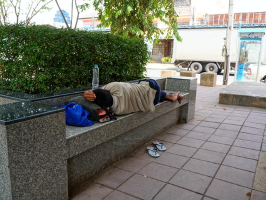 homeless man sleeping on city bench
