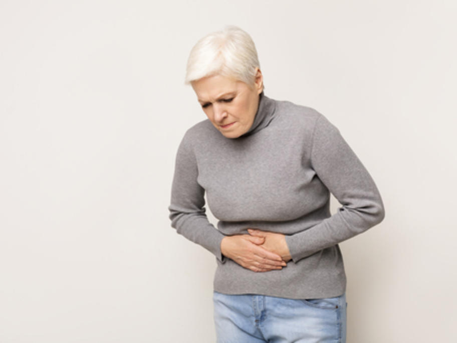 anxious senior woman clutching her abdomen