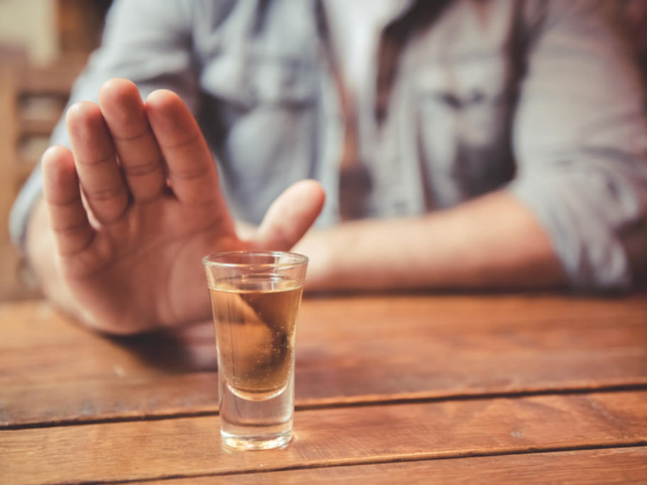 Man saying no to alcohol - hand pushing it away