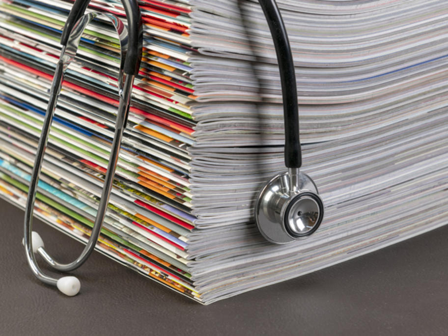 Pile of medical journals with stehoscope draped over them