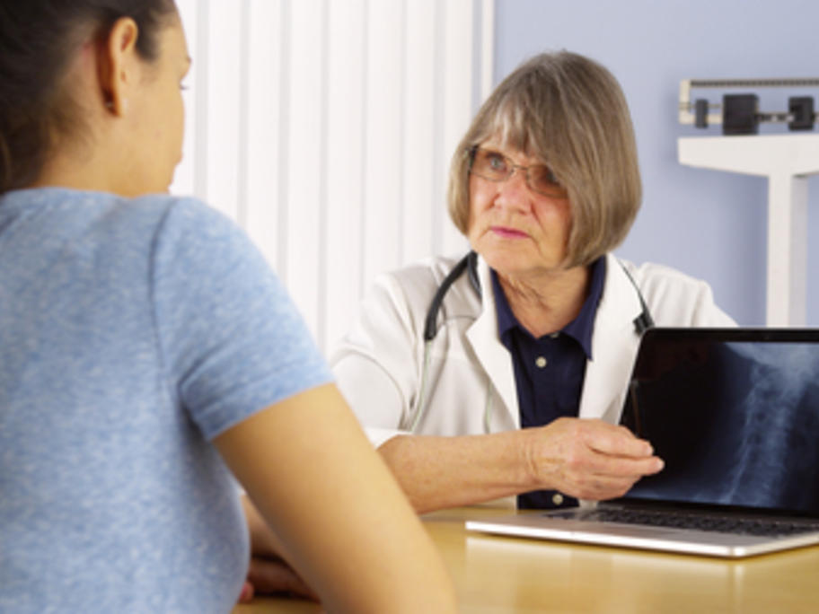 Doctor showing young female patient neck X-ray