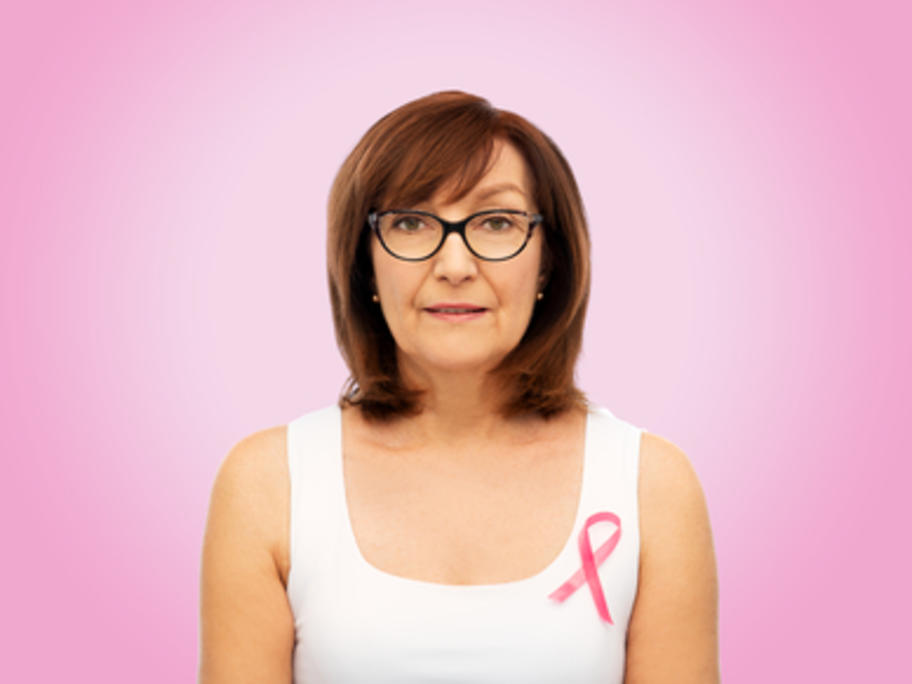 postmenopausal woman against pink background wearing ribbon
