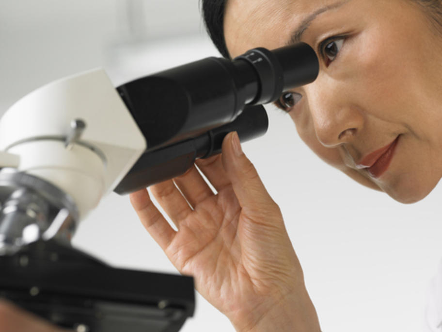 female pathologist looking down microscope