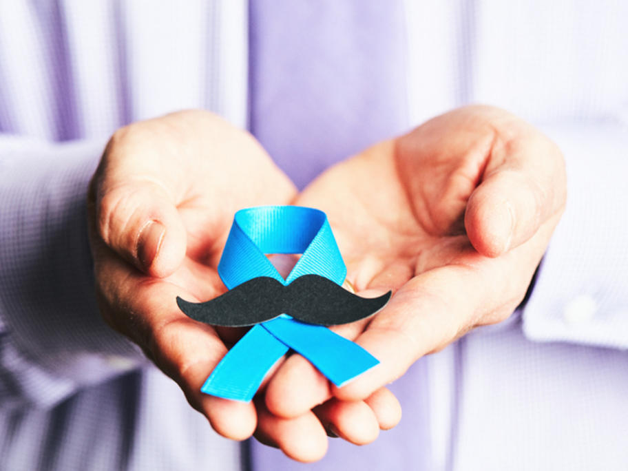 man holding blue ribbon with moustach signifying prostate cancer
