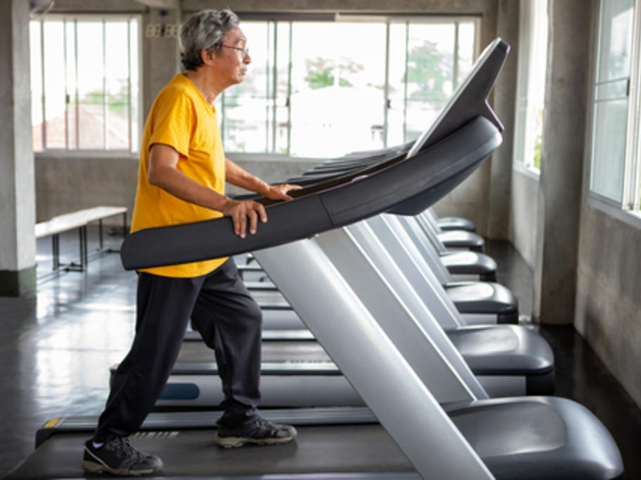 Older Asian man walking on treadmill
