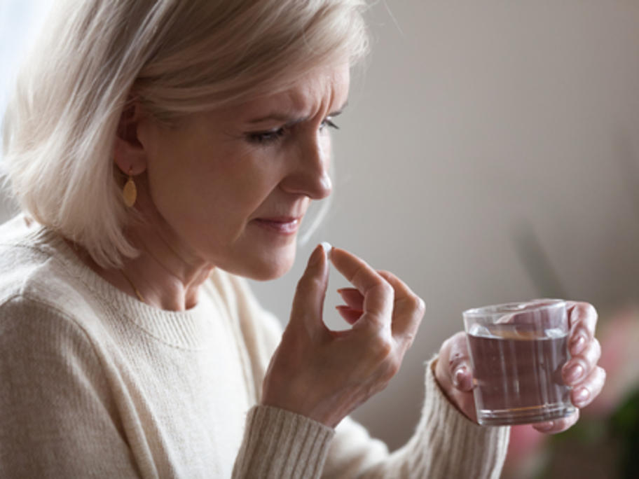 senior woman taking a pill with water
