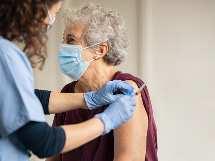 senior woman wearing mask having vaccination