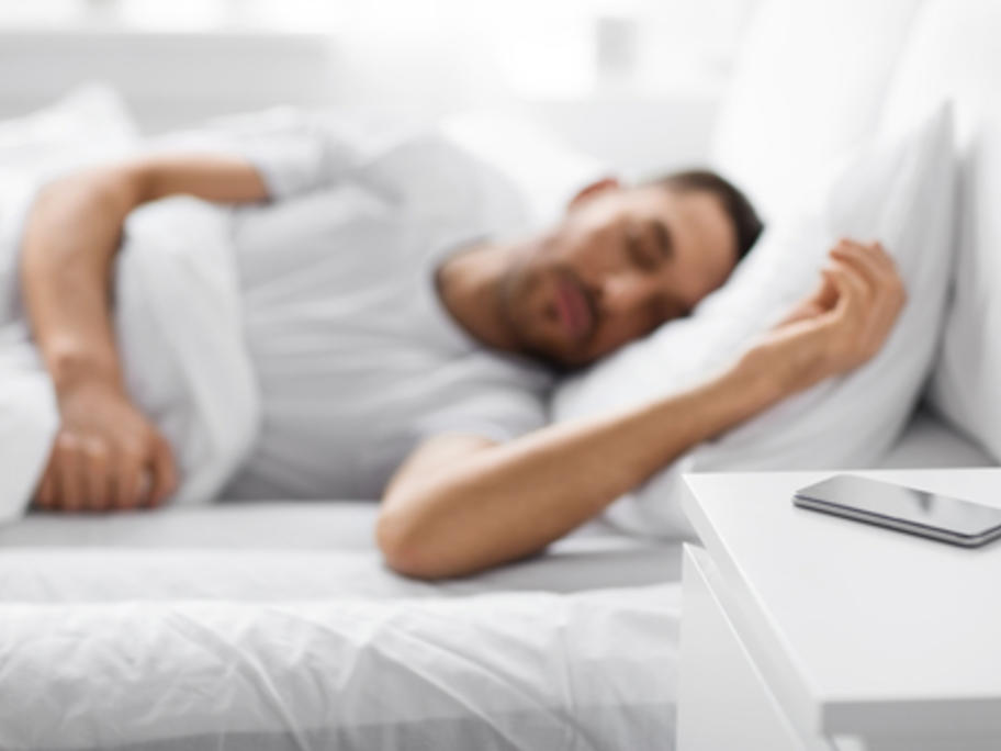 sleeping man with smartphone by his bed