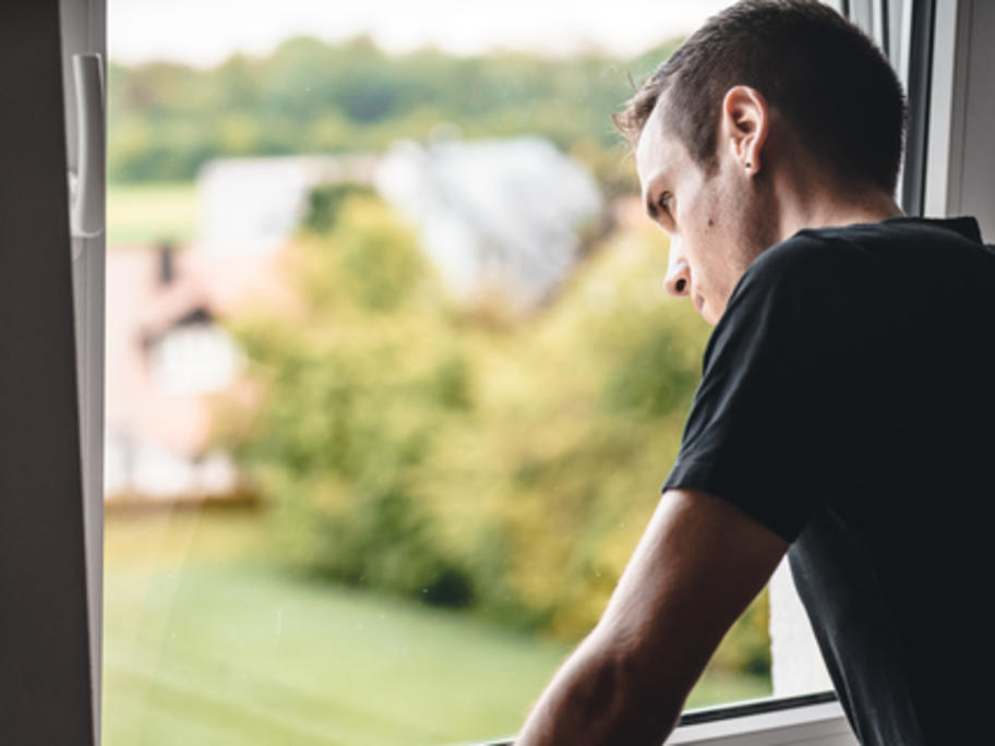 Depressed young man looking out of the window