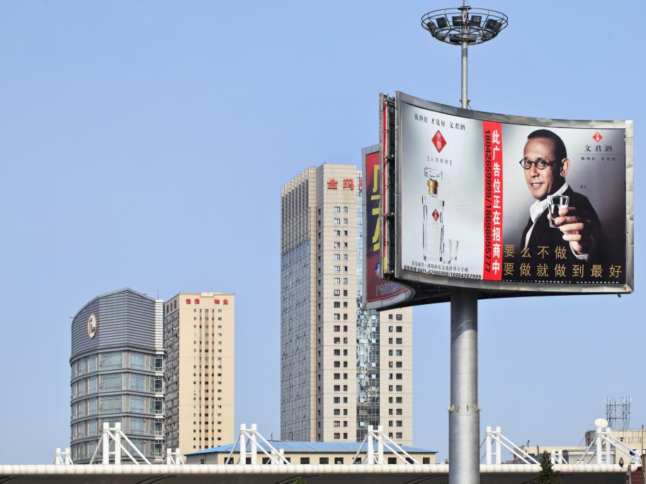 China- skyscrapers and billboard showing man holding glass of baijiu (rice wine)