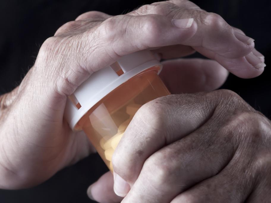 arthritic hands opening a pill bottle