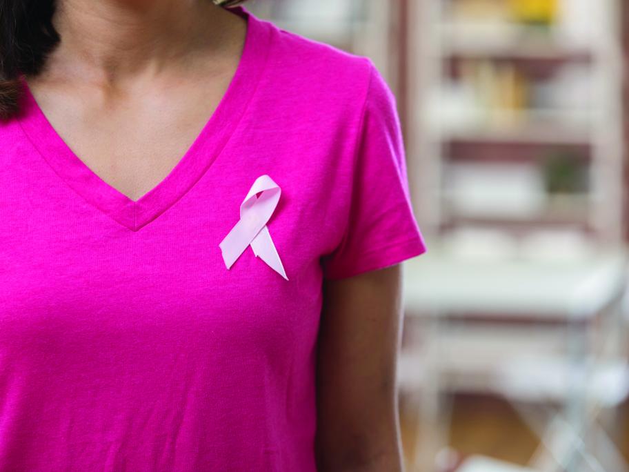 Woman in pink t-shirt with pink ribbon, denoting breast cancer
