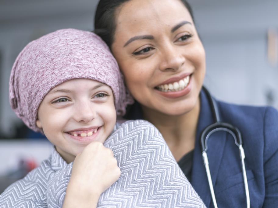 child with cancer sitting on doctor's lap