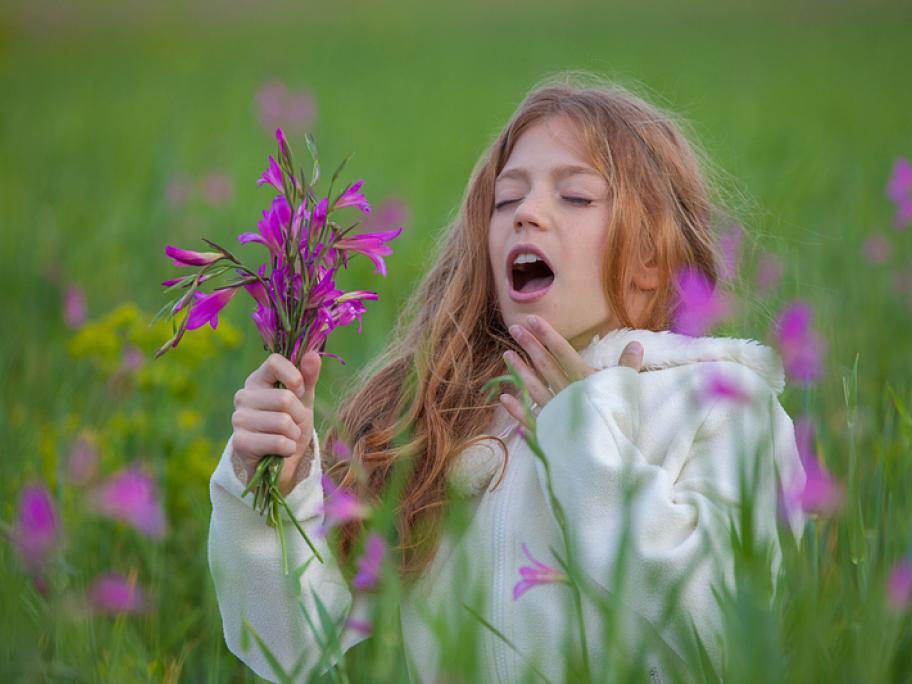 Girl sneezing in field of flowers