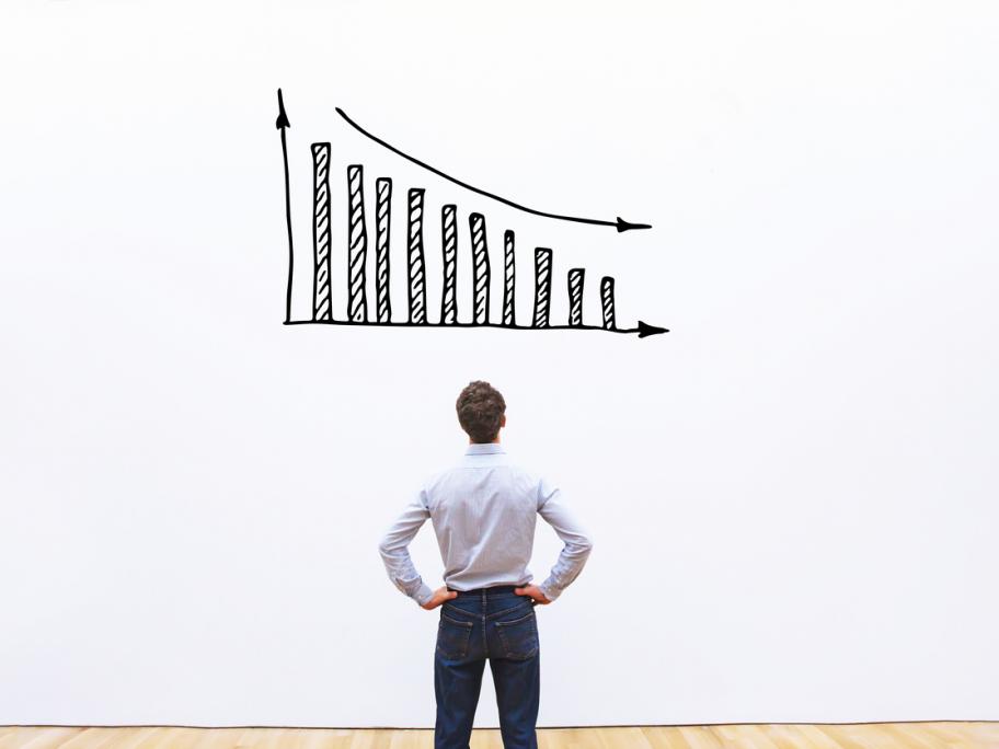 man looking at decreasing graph on white wall