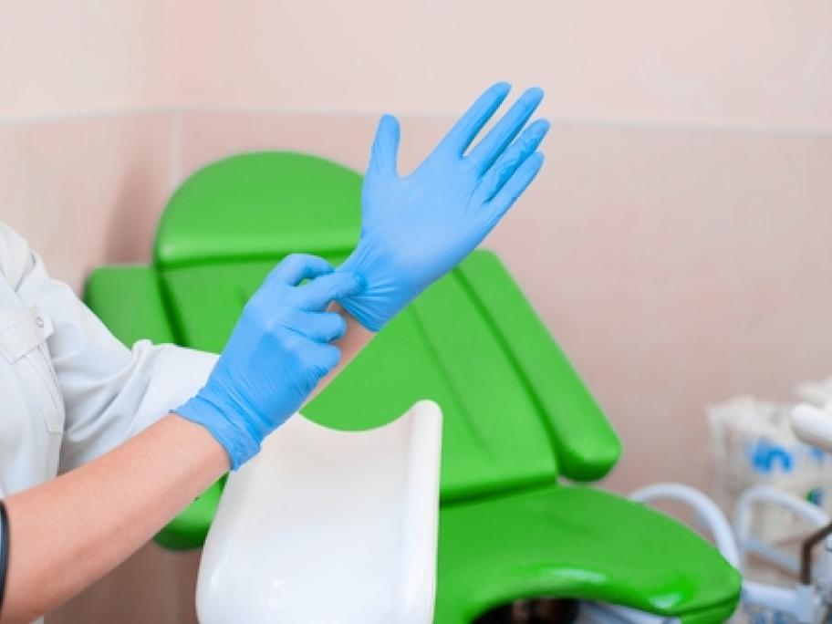 gynaecologist putting on gloves prior to examining patient