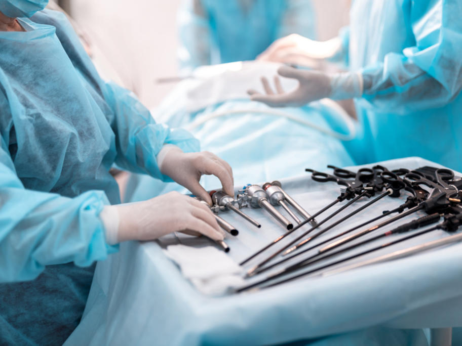 thatre nurse with tray of laparascopis instruments