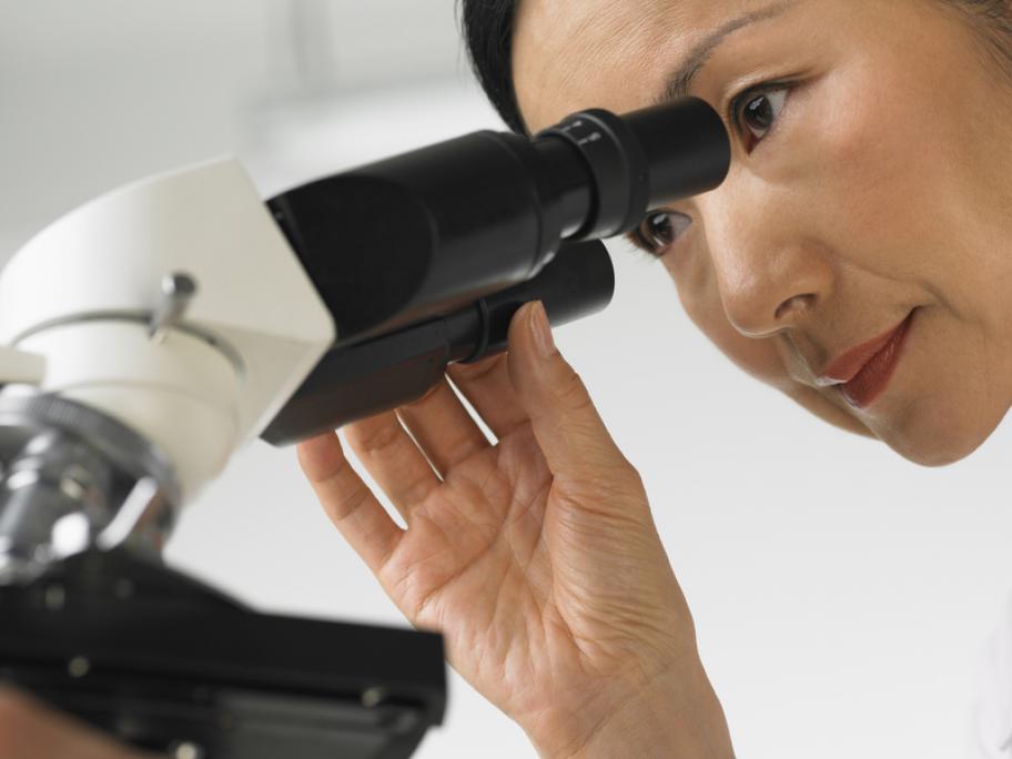 pathologist looking down a microscope