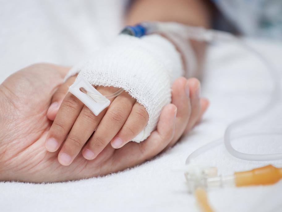 mother holding child's hand while child having drip
