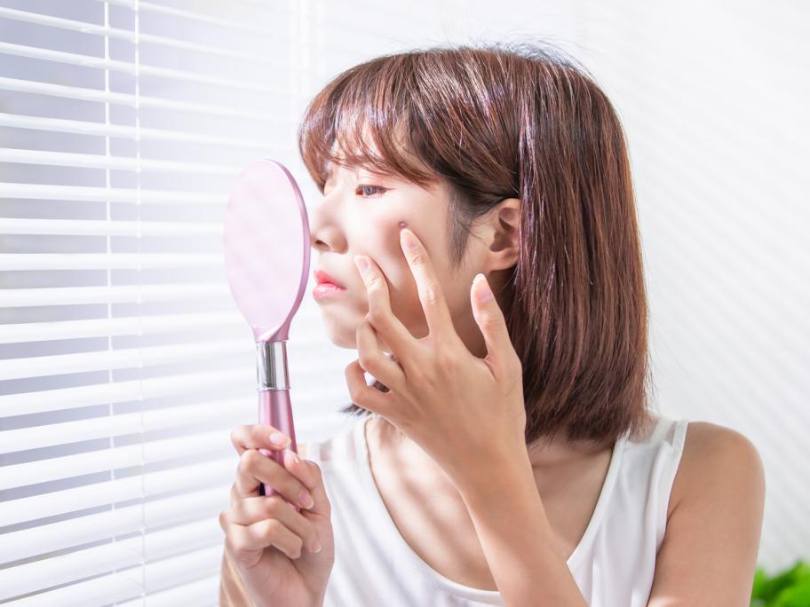 Woman looking at face in mirror