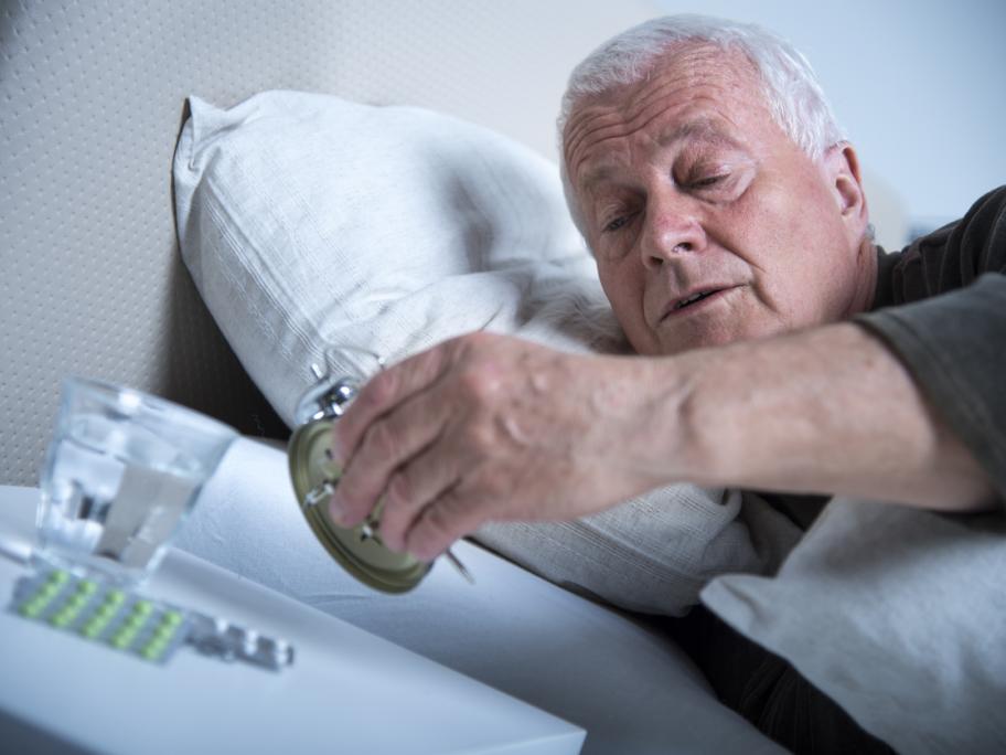 Man in bed looking at clock