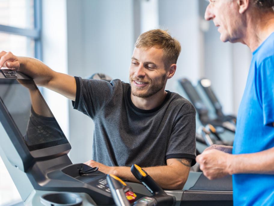 Man running on treadmill with physio helping