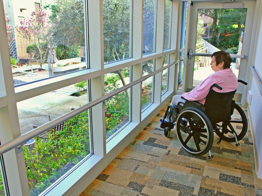 Woman in wheelchair happy looking out of window at garden