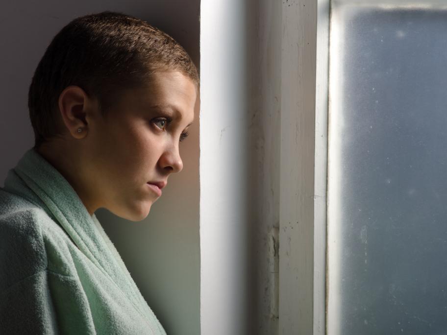 Young woman with shaven hair - cancer patient - looking sad