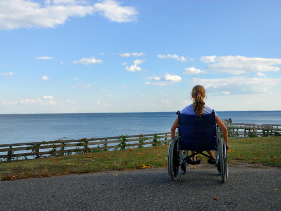 Young woman in wheelchair looking at view of sea