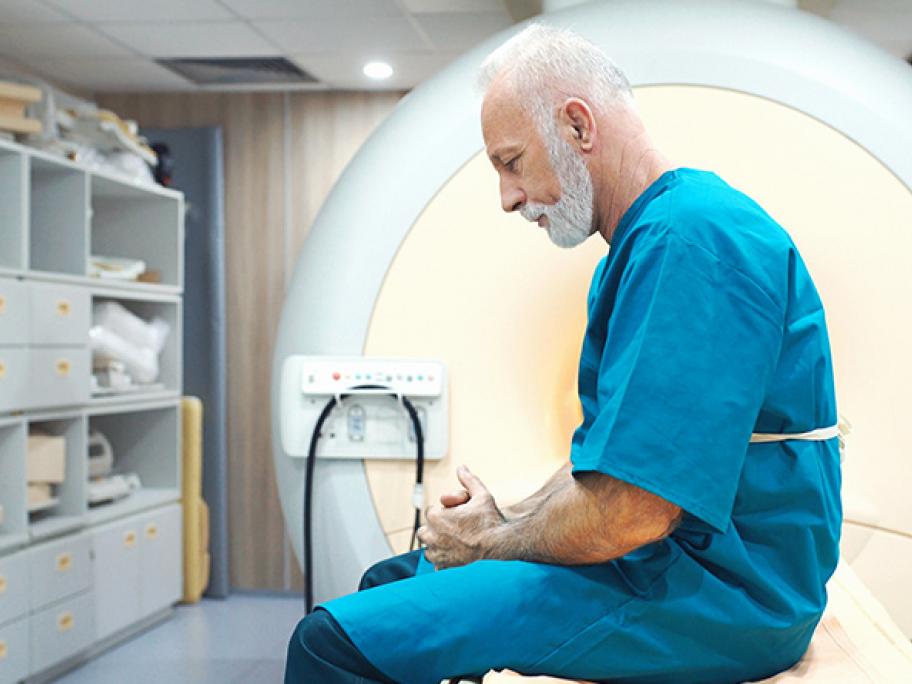 Senior man looking worried sitting in front of MRI scanner