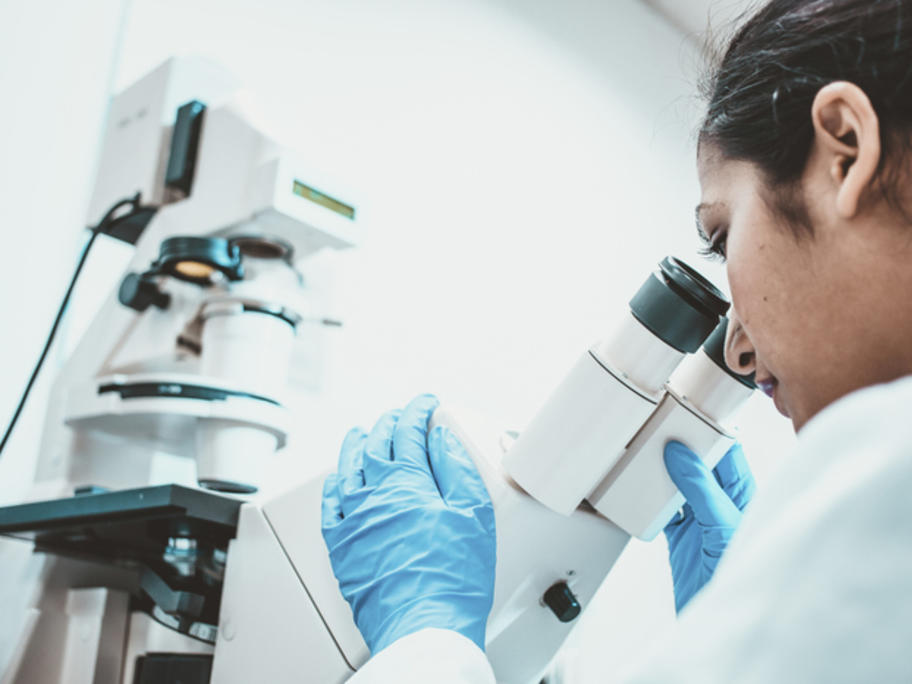 pathologist looking down a microscope