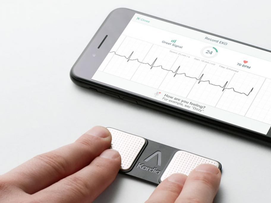 AliveCor monitor with person touching it with 2 fingers from each hand and smartphone showing ECG
